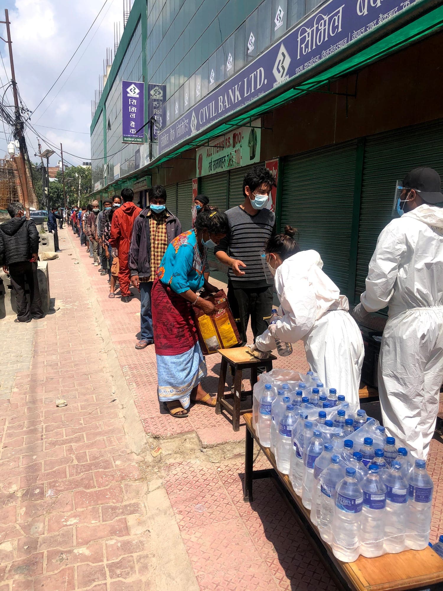 A long, distanced queue along a closed street, waiting for food and water