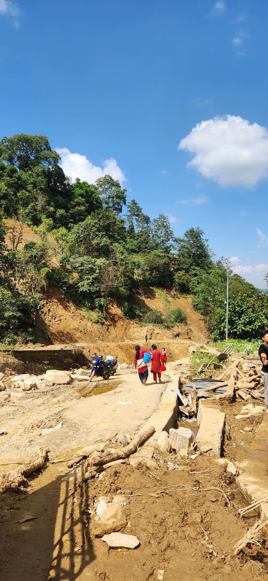 A road broken by the flood, with people walking in the distance