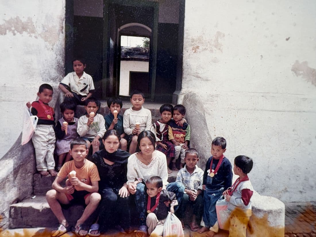 Pooja sitting with a group of children on the steps of a building
