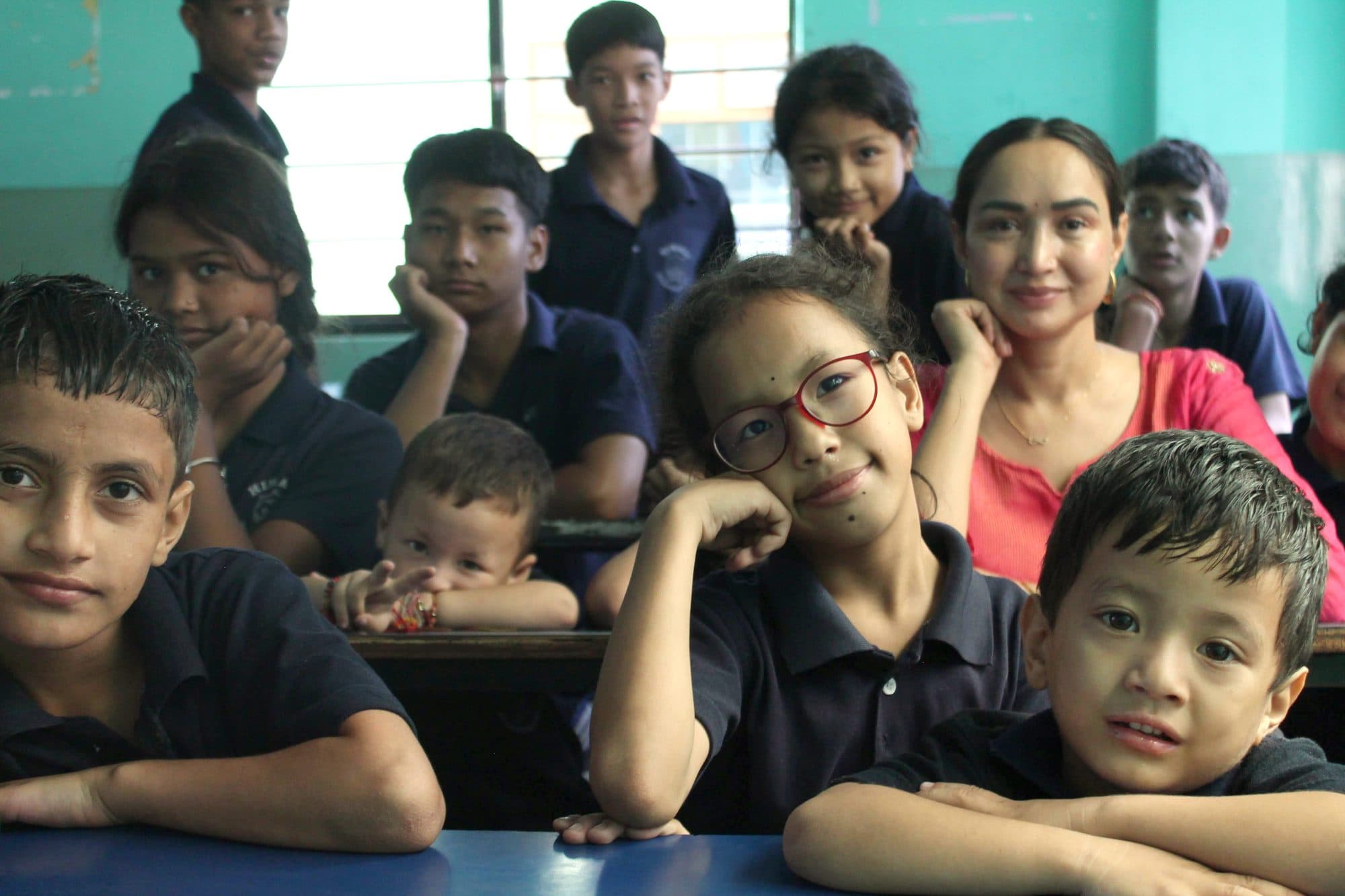 Pooja today in a classroom, sitting among the children Bhagya Nepal supports, chins resting on their hands