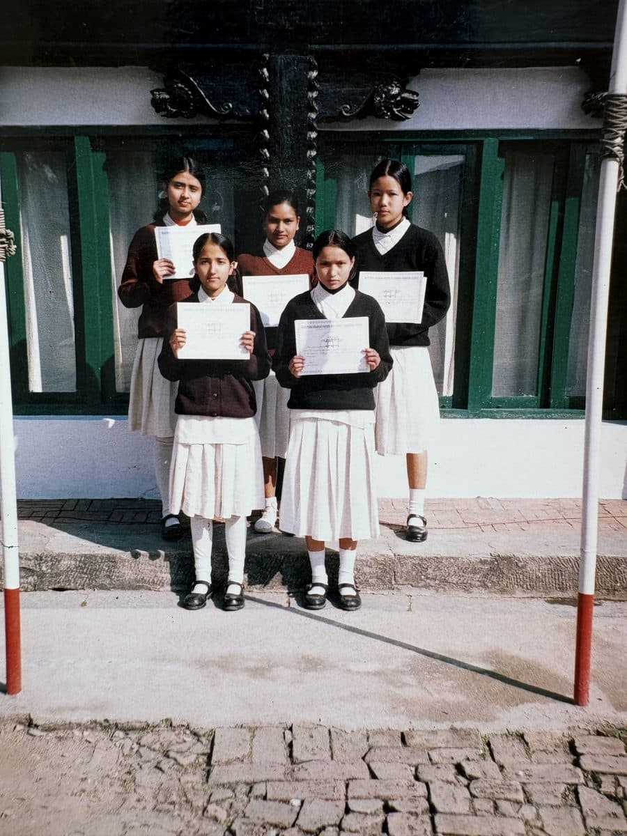 Pooja with her classmates in school uniform, each holding a certificate