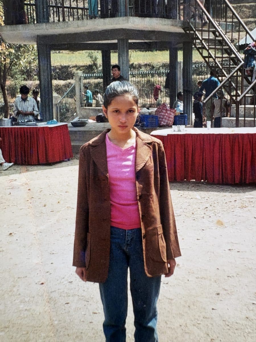 Pooja as a teenager, standing alone in a courtyard