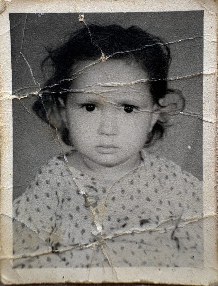 Pooja as a young child, an old cracked print