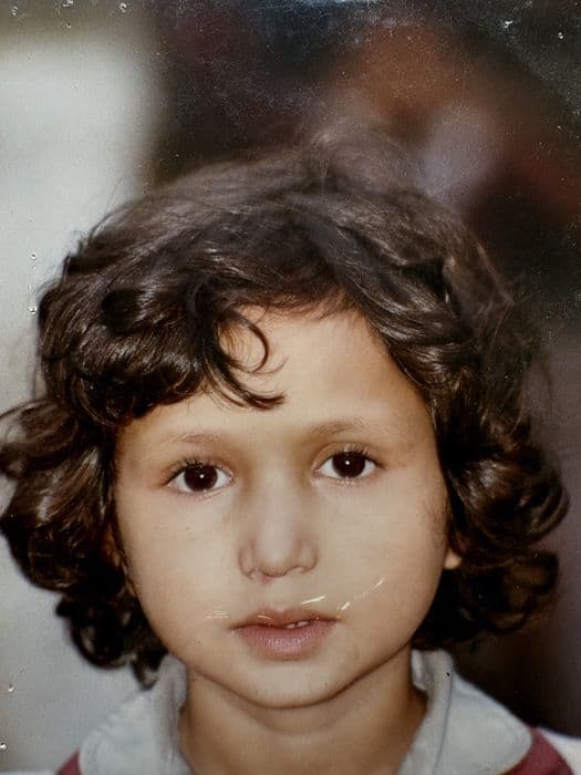 Pooja as a little girl with curly hair, an old colour print