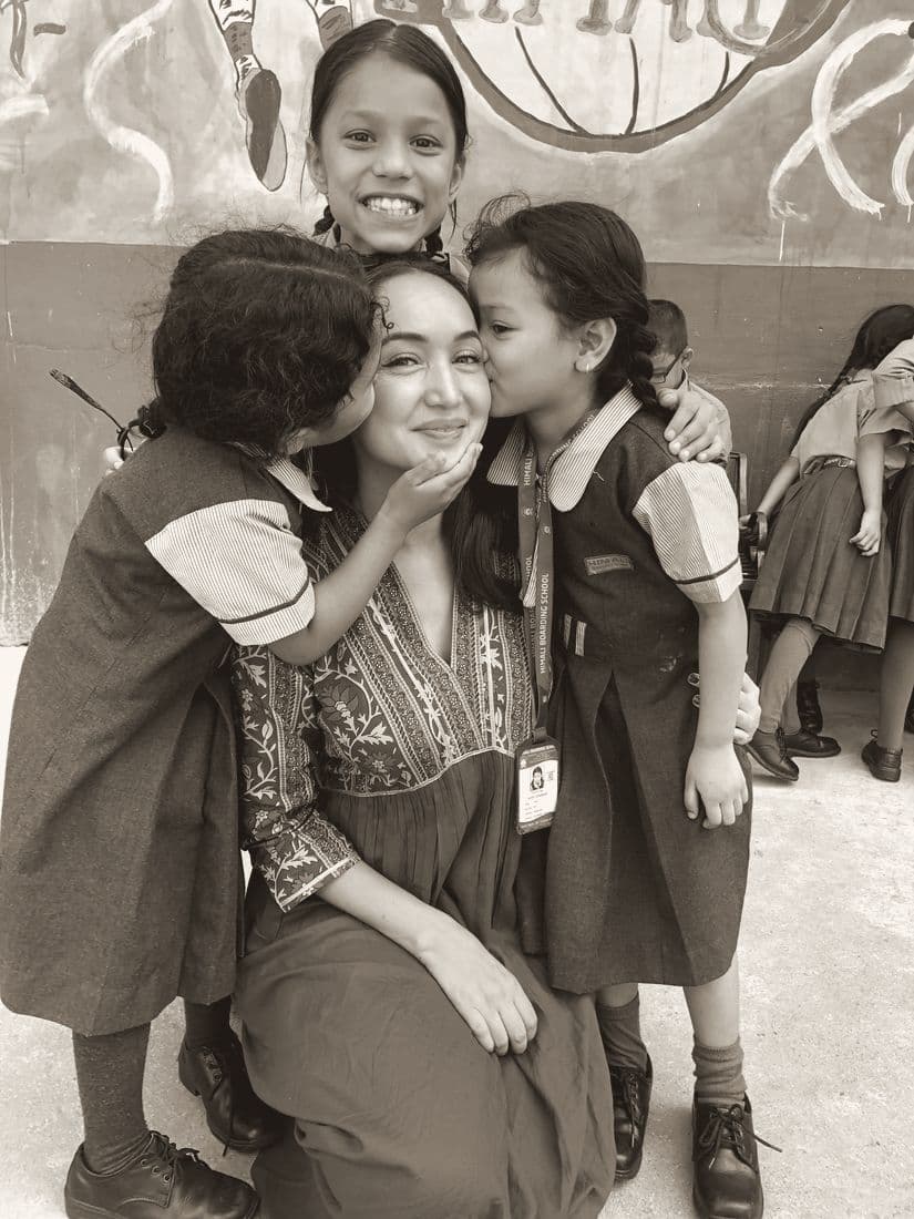 Two girls kissing Pooja on the cheeks