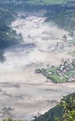 The flood spreading across the valley around a cluster of houses