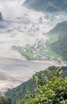Floodwater surrounding a village on a strip of green land