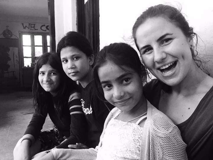 Black-and-white photo of three young girls at Bal Mandir with a volunteer, all smiling