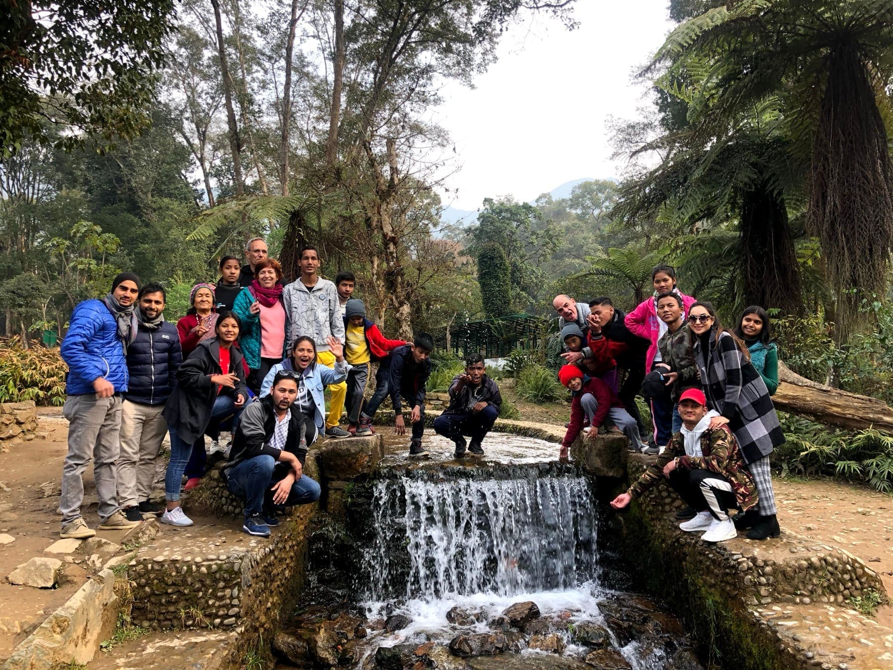 The Ruta6 team, Pooja and the children gathered around a small waterfall in a forest